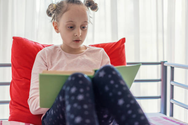istock Young girl reading book in her room 1152031857