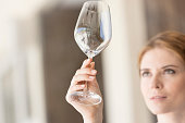 Closeup of young waitress looking at empty wineglass in restaurant