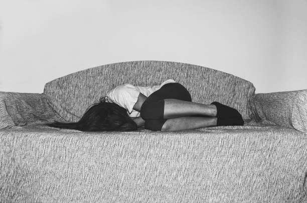 depressed and lonely girl abused as young lies alone in her room on the bed feeling miserable and anxiety cry over her life, dark image black and white hard contrast - unemployment fear depression women imagens e fotografias de stock