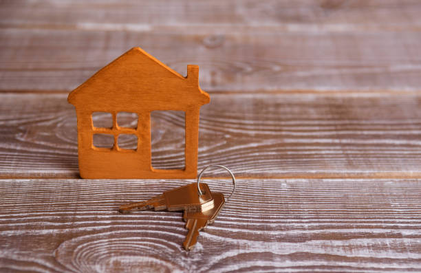 istock house, two keys on wooden background. 1152035299