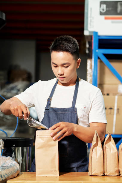 istock Man packing coffee beans for sale 1152035929