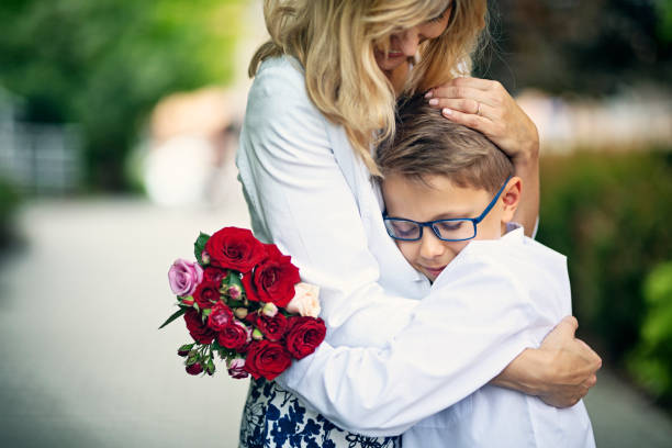 It's mother's day. Little boys aged 9 is giving roses to his mother. The boy is hugging his mother.\nNikon D850