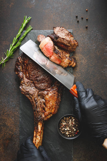 istock Man in black gloves cuts dry-aged marble beef steak Tomahawk. Top view, dinner concept. 1152043248