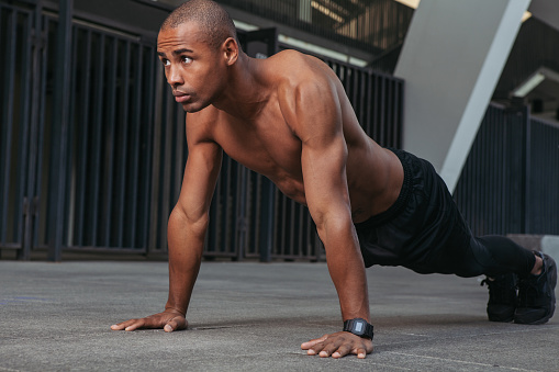 Handsome muscular man doing push ups outdoors