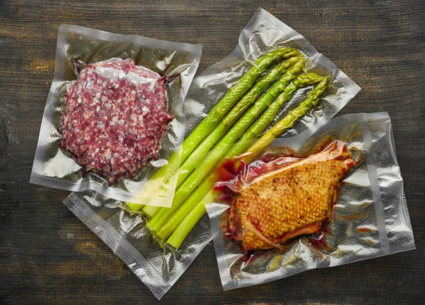 Duck breast, burger meat and asparagus vacuum sealed, top view Duck breast, burger meat and asparagus vacuum sealed on wooden table ready for sous vide cooking, from above airtight photos stock pictures, royalty-free photos & images