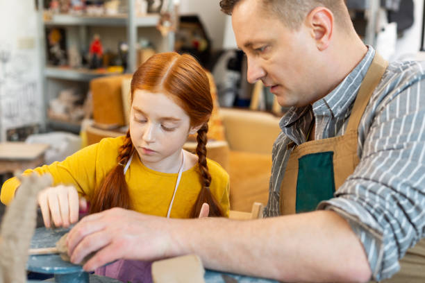 istock Art teacher assisting his appealing red-haired pupil 1152050079