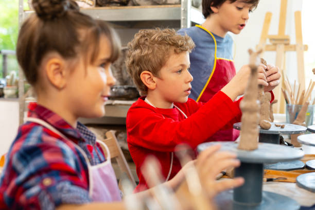 istock Blonde boy sitting near classmates and modeling clay animals 1152050308
