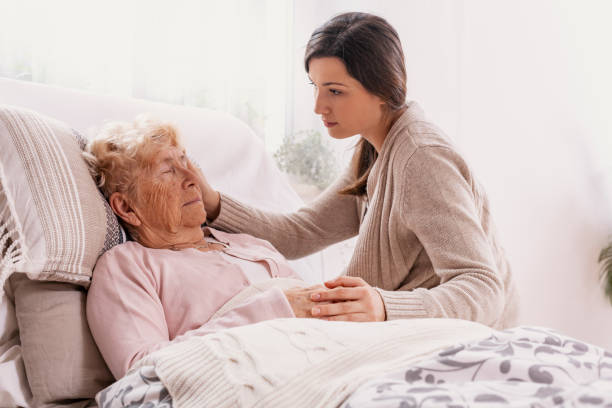 istock Young daughter supporting sick mother lying in hospital bed 1152051809