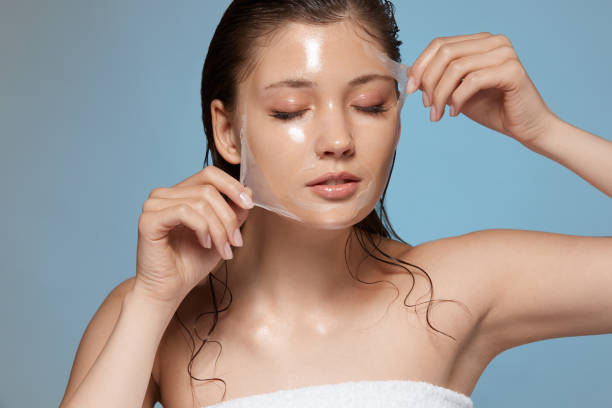 mujer bonita sacando la máscara purificadora con los ojos cerrados - mimarse fotografías e imágenes de stock