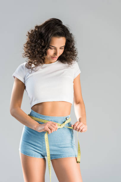 istock Slim brunette girl using measuring tape isolated on grey 1152053385