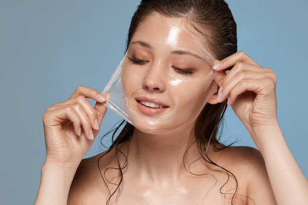 young and happy woman removes facial mask and looking down to the side stock photo