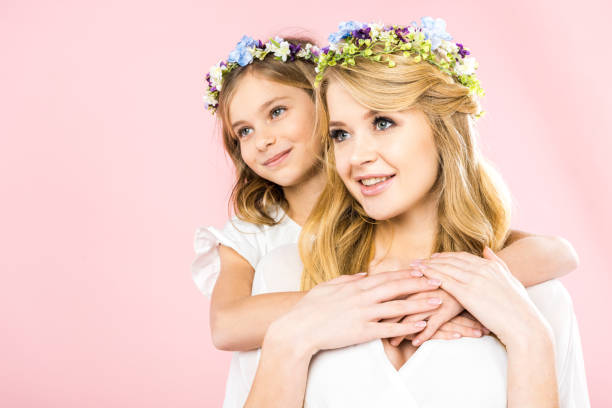 istock smiling child hugging beautiful mother from back on pink background 1152053647