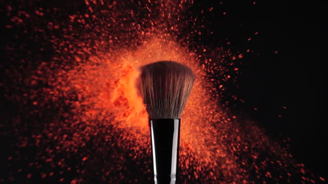 Slow motion: Makeup Brush and red powder exploding