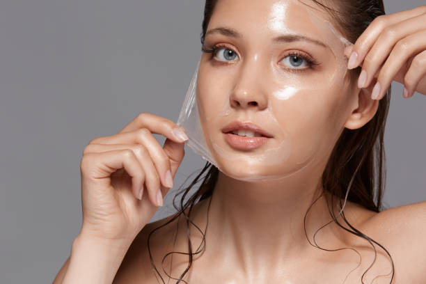 beautiful woman removing peeling mask from her face and looking to the camera stock photo
