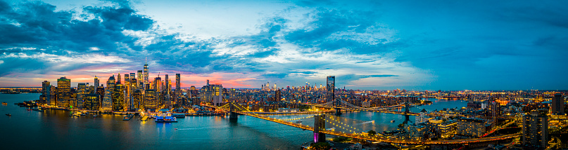 An aerial panoramic image of the Manhattan skyline at night in New York.