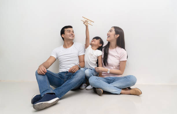 glückliche multiethnische familie, die auf dem boden sitzt und gemeinsam spielzeugflugzeug spielt. familien-und kindheitskonzept. - korea child baby asian culture stock-fotos und bilder