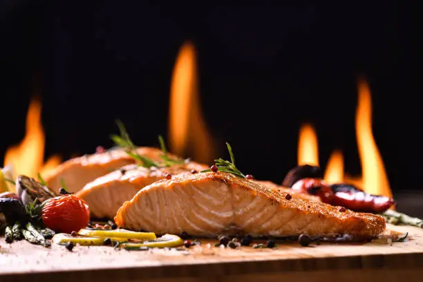Photo of Grilled salmon fish and various vegetables on wooden table background