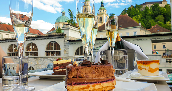Close up of glasses of champagne and cakes at Triple bridge promenade at Ljubljanica river.