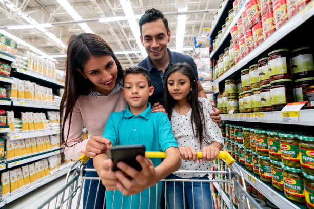istock Little boy holding smartphone while everyone else looks at the shopping list 1152072067