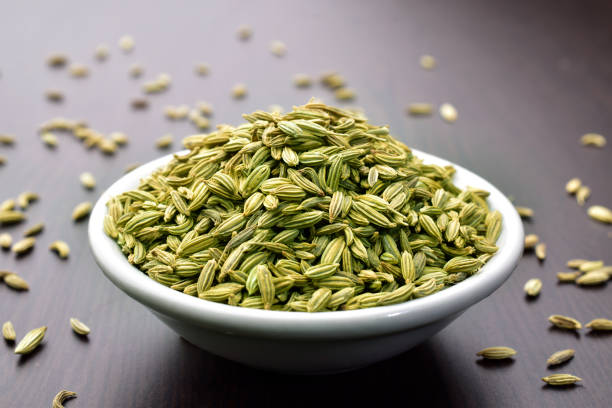 Fennel seeds in a bowl on a wooden table stock photo