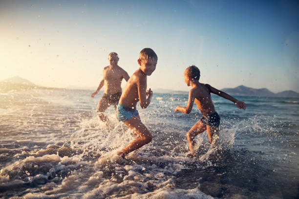 padre jugando a la etiqueta con los niños en la playa - child running playing tag fotografías e imágenes de stock