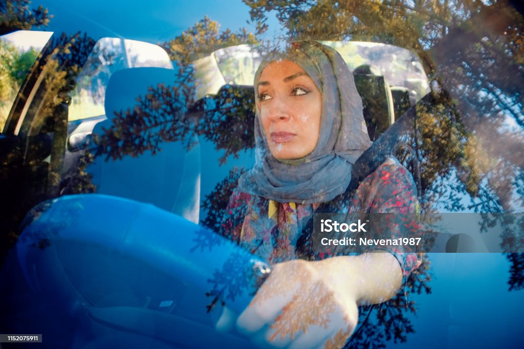 Muslim woman driving a car and smiling Dubai, Persian Gulf Countries, United Arab Emirates, 2015, 25-29 Years Driving Stock Photo