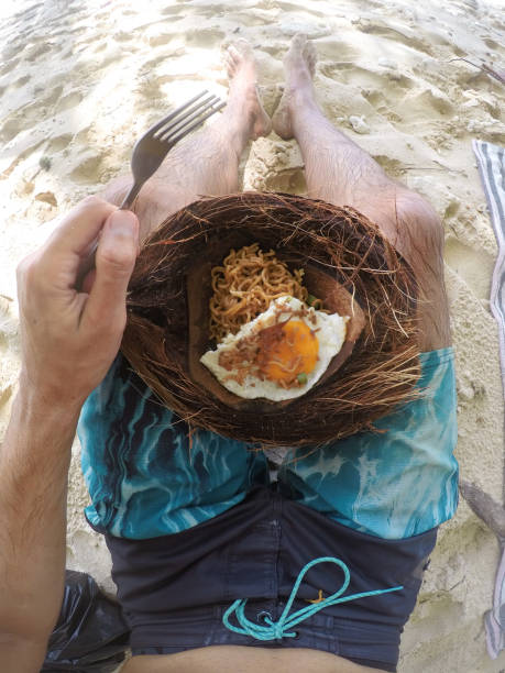 hombre comiendo fideos de coco - mentawai islands rural scene sumatra indonesia fotografías e imágenes de stock