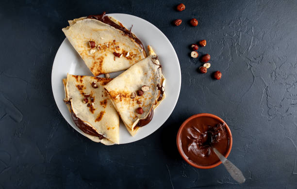 istock Pancakes with chocolate paste and hazelnuts, on a white plate on a background of concrete, slate 1152081844