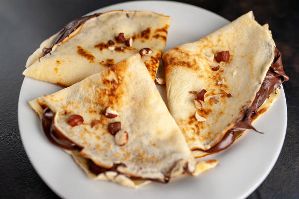 istock Pancakes with chocolate paste and hazelnuts, on a white plate on a background of concrete, slate 1152081920