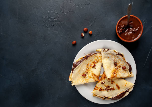 istock Pancakes with chocolate paste and hazelnuts, on a white plate on a background of concrete, slate 1152081925