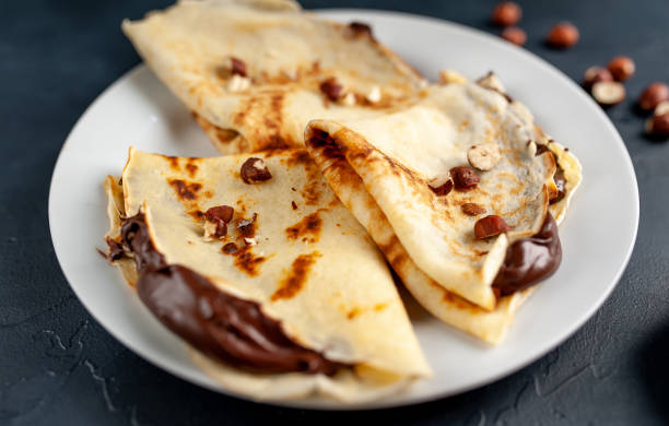 istock Pancakes with chocolate paste and hazelnuts, on a white plate on a background of concrete, slate 1152081930