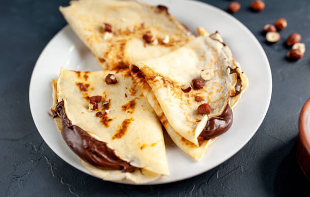 istock Pancakes with chocolate paste and hazelnuts, on a white plate on a background of concrete, slate 1152081931