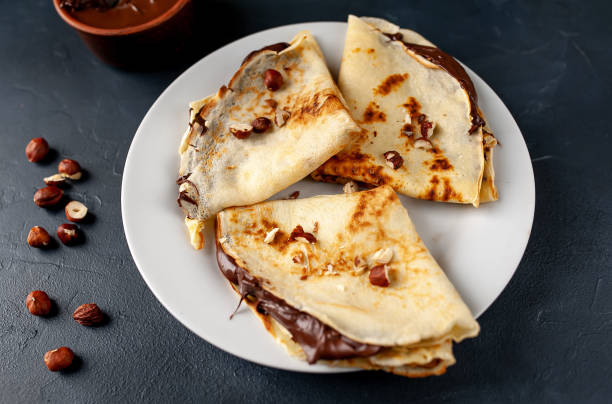istock Pancakes with chocolate paste and hazelnuts, on a white plate on a background of concrete, slate 1152081935