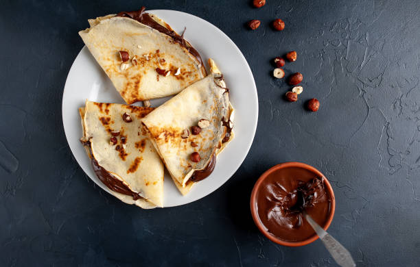 istock Pancakes with chocolate paste and hazelnuts, on a white plate on a background of concrete, slate 1152081941