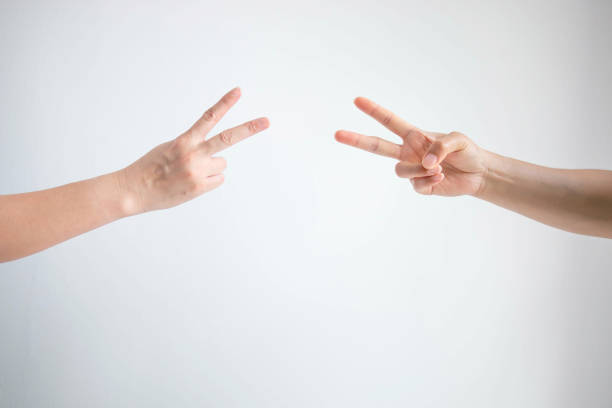 istock Two person playing rock paper scissors with both posturing scissors symbol on white background. 1152082041