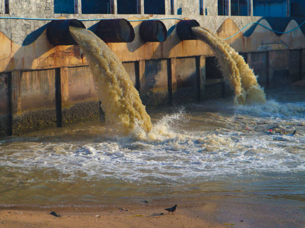 tubulação industrial e da descarga da água waste da fábrica no canal e no mar - seaside industrial - fotografias e filmes do acervo