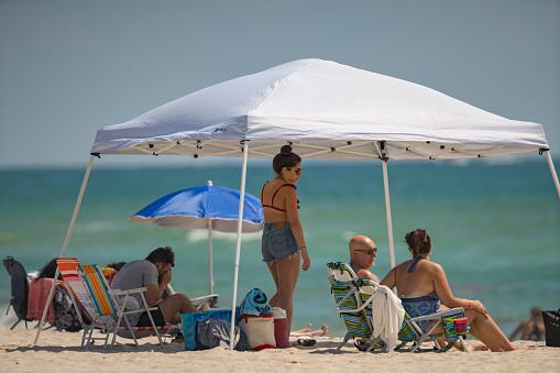 Hollywood, FL, USA - May 27, 2019: Family on the beach under a tent Memorial Day
