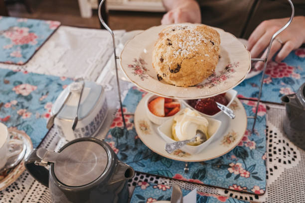 focaccine di frutta, marmellata e panna, note come tè pomeridiano nel regno unito, servite su un vassoio vintage su un tavolo. - afternoon tea scone tea cream foto e immagini stock