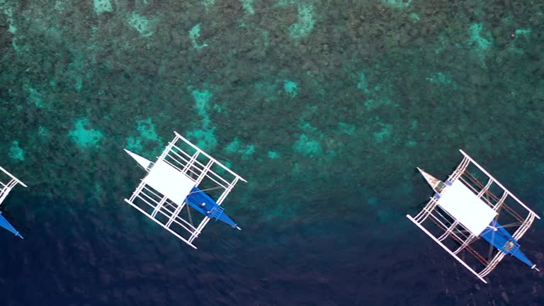 Aerial view of Filipino boats floating on top of clear blue waters, Oslob is a deep clean blue ocean and has many local Filipino boats, Oslob, Cebu, Philippines.