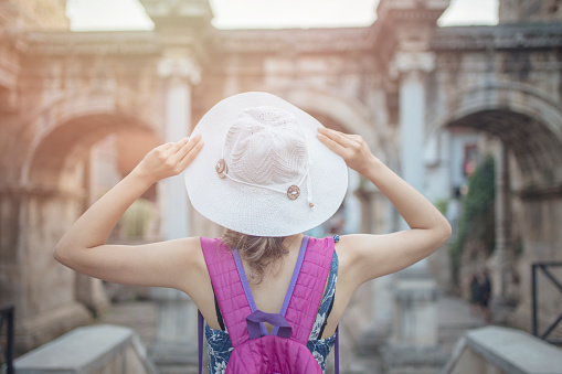 back view of traveler girl holding her hat