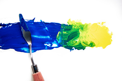 Paint being blended with palette knife, Yellow and Blue makes Green
