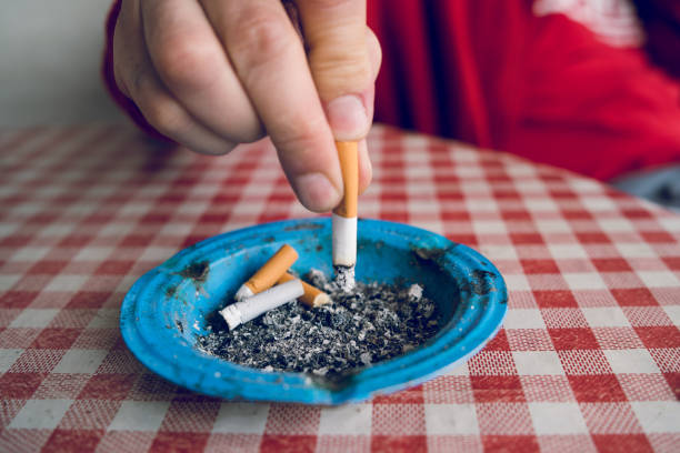 cerca de man man extingue el cigarrillo en la bandeja de ceniza dejando de fumar problemas de salud pulmonar - cenicero fotografías e imágenes de stock