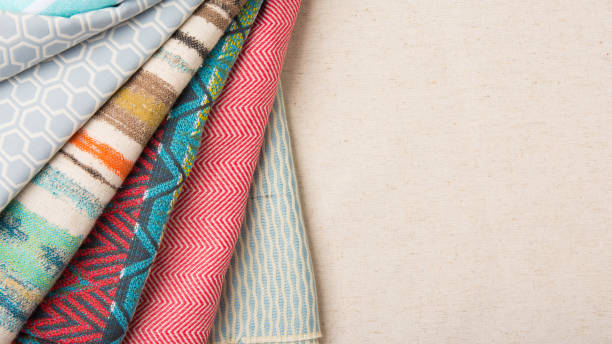una varietà di tessuti colorati piegati e disposti su un tavolo di tela con spazio di copia per il testo. - quilt patchwork sewing textile foto e immagini stock