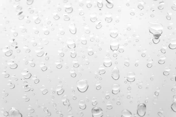 Water drops on glass white gray background.