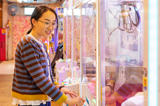 Young Asian Woman Playing the Claw Game in an Arcade