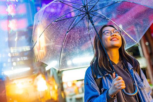 Portrait of a Smiling Happy Young Asian Woman Lit By Vibrant Neon Lights in the Rain