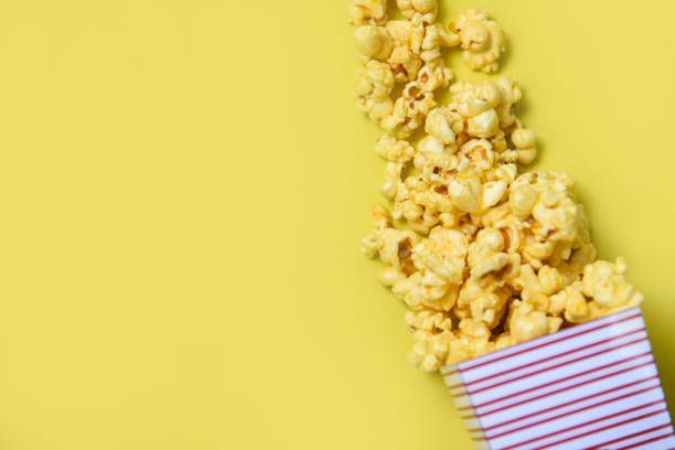 istock Popcorn cup box on yellow top view - Sweet butter popcorn background 1152122372