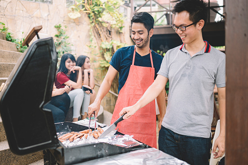 a group of asian multi ethic young adults gathering at villa during weekend for city break enjoying barbecue session