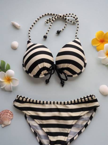 istock Black and white stripe bikini with plumeria flowers and seashells on light blue background. 1152124906