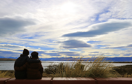 Silhouette of a happy couple relaxing on Argentino lake shore in El Calafate, Patagonia, Argentina, South America